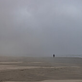 Neblige Gestalt geht am Strand entlang