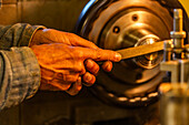 Hände eines erfahrenen Holz- und Metallhandwerkers bei der Arbeit mit Werkzeugen in der Werkstatt
