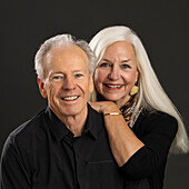 Studio-Porträt eines älteren Paares in schwarzen Hemden vor dunklem Hintergrund