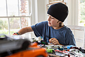 Boy (10-11) playing with toy cars at home