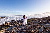 Südafrika, Hermanus, Junge (10-11) läuft auf Felsen am Kammabaai Beach