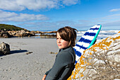 Junge (10-11) mit Bodyboard beim Entspannen am Voelklip Beach