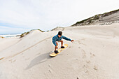 Boy (10-11) sand boarding in Walker Bay Nature Reserve