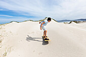 Junge (10-11) beim Sandboarden im Walker Bay Naturreservat