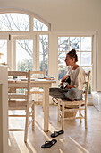 Teenage girl (16-17) playing guitar in dining room