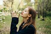 Schöne Frau riecht an einer Blume im Obstgarten