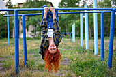 Redhaired woman hanging on bars at playground