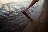 Nahaufnahme einer Frau, die bei Sonnenuntergang Wasser im Fluss berührt
