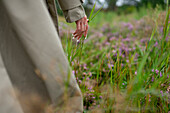 Close-up of woman in trench coat touching grass