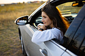 Young woman looking through window while driving car 