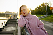 Portrait of serious woman leaning on railing at sunrise