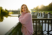Porträt einer reifen Frau, die bei Sonnenaufgang am Fluss steht