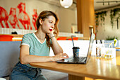 Serious woman working on laptop in cafe 