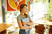 Porträt einer Frau, die mit einem Laptop in einem Café steht