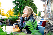 Nachdenkliche Frau trinkt Kaffee in einem Straßencafé