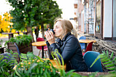Nachdenkliche Frau trinkt Kaffee in einem Straßencafé