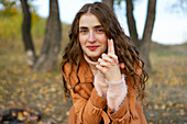 Portrait of smiling woman with hands clasped in park