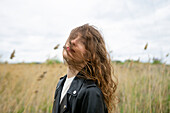 Portrait of woman standing in field on windy day