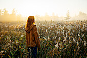 Rückansicht einer Frau, die bei Sonnenaufgang auf einem Feld steht