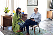 Patientin im Gespräch mit einem Mann während einer Psychotherapie zu Hause