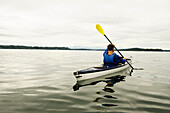 Mann fährt Kajak auf einem See