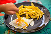 Young Child Enjoying Fries and Eggs