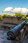 Eine alte spanische Kanone schützt die alte Kolonialstadt Santo Domingo, Dominikanische Republik, vor Piraten. UNESCO-Weltkulturerbe der Kolonialstadt Santo Domingo. Im Hintergrund liegt das luxuriöse Kreuzfahrtschiff Sea Cloud vor Anker.