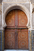 Fes, Marokko. Atemberaubende handbemalte Tür einer alten Moschee mit handgeschnitzten Stuckarbeiten.