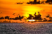 The crimson light of the setting sun reflects a red glow on the beach at Pererenan Beach, Bali, Indonesia