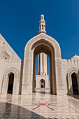 Ein Torbogen, der zu einem Minarett in der Großen Sultan-Qaboos-Moschee in Maskat, Oman, führt.