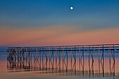 Canada, Manitoba, Matlock. Pier on Lake Winnipeg at dusk with moon.