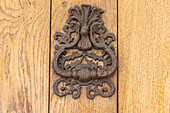 Aigues-Mortes, Gard, Occitania, France. An old rusted knocker on a wooden door.