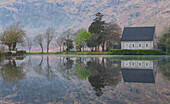 Irland, Cork, Gougane Barra. Kirche und Berge spiegeln sich im See.