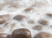 Ireland, Kinard. Close-up of wave on smooth beach rocks.