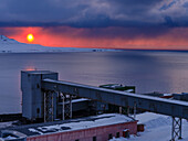 Sonnenuntergang über dem Bergwerk. Russische Kohlebergbaustadt Barentsburg am Fjord Gronfjorden. Die Kohlemine ist noch in Betrieb. Arktische Region, Skandinavien, Norwegen, Svalbard