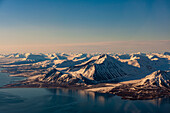 Sonnenlicht beleuchtet die eisbedeckten Berge auf der Insel Spitzbergen, Svalbard, Norwegen.