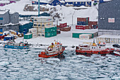Fischerboote im zugefrorenen Hafen während eines Schneesturms. Ilulissat, Grönland. (Nur für redaktionelle Zwecke)