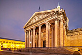 Die neoklassizistische Fassade des Panthéon ist in der Abenddämmerung beleuchtet.