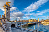 Grand bridge in Paris, Pont Alexandre III, with a majestic statue on top, spanning a body of water.