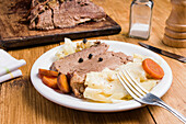 Tasty homemade corned meat with cabbages pieces of carrot served on plate on wooden table