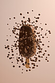 Seitenansicht eines surrealen Schokoladeneises, umgeben von in der Luft schwebenden Schokoladenkugeln