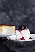 Delicious slices of baked cheesecake topped with berry jam served on a plate on black background