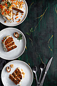Draufsicht auf leckeren Kuchen mit Frischkäse, serviert auf Tellern mit frischen Karottenscheiben und Walnüssen