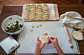 From above of crop anonymous female cook stuffing dough with meat while preparing traditional Chinese dumplings in kitchen