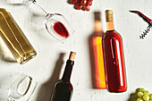 Arrangement feiner Rot- und Weißweine auf rissiger Oberfläche inmitten von Weingläsern und Trauben