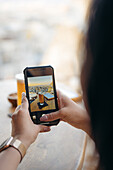 Crop anonymous female customer taking picture with mobile phone of beer and snacks in bar