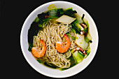 From above bowl of tasty seafood noodles on black wooden table in Asian cafe