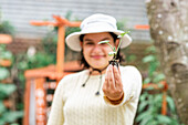 Selective focus of small seedling in hands of positive female gardener working in farm