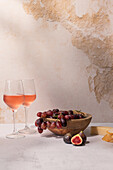 Gläser mit rotem Getränk stehen auf einem Tisch mit einer Schale mit Trauben und Feigen neben Baguettescheiben