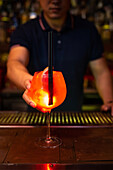 Young Asian bartender gives you a grapefruit juice gin cocktail in the bar after he finished to prepare it